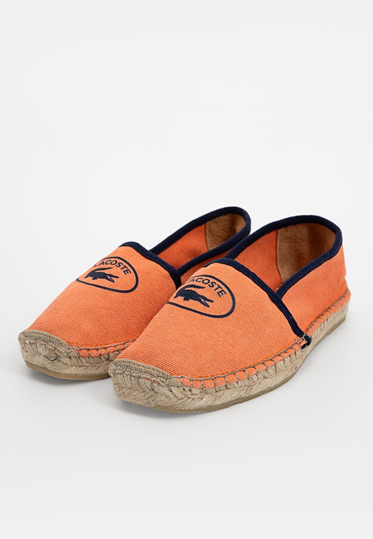 Espadrillas di tela arancione con bordo blu navy e un logo circolare con design di coccodrillo. Suola in espadrilla realizzata in juta.