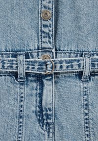 Vêtement en denim bleu clair avec des boutons métalliques portant l'inscription « Blue Ridge » et une ceinture assortie en tissu avec une boucle anneau en métal.