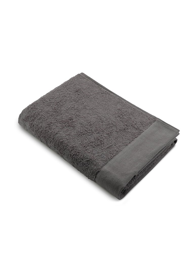 Grijze katoenen handdoek, pluizige textuur, rechthoekige vorm, met een gladde, vlakke geweven rand langs één zijde.
