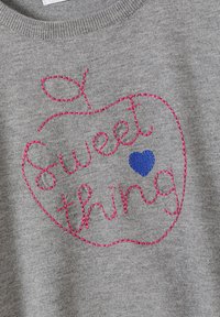 Szürke pulóver rózsaszín hímzett almával, mellette a "Sweet thing" felirattal és egy kék szívvel. Kerek nyakkivágással és puha textúrával rendelkezik.