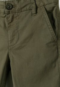 Olijfgroene chino's gemaakt van een katoenmix, met een voorzak en knoopsluiting, en zichtbare stikseldetails.