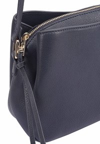 Donkerblauwe leren crossbody tas met gestructureerd oppervlak, hardware in goudtint, ritssluiting aan de bovenkant en verstelbare schouderriem.