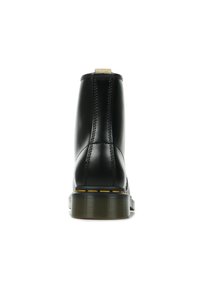 Stivaletto in pelle nera con una texture liscia, dettagli cuciti, bordo della suola gialla e un piccolo etichetta con logo sul retro.