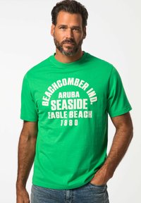 Zelené bavlněné tričko s tučným bílým textem: "BEACHCOMBER IND. ARUBA SEASIDE EAGLE BEACH 1880." Klasický kulatý výstřih a krátké rukávy.
