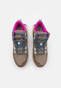 Brown outdoor sneakers with mesh upper, pink and blue laces, and light blue accents. Rugged sole with textured patterns for grip.
