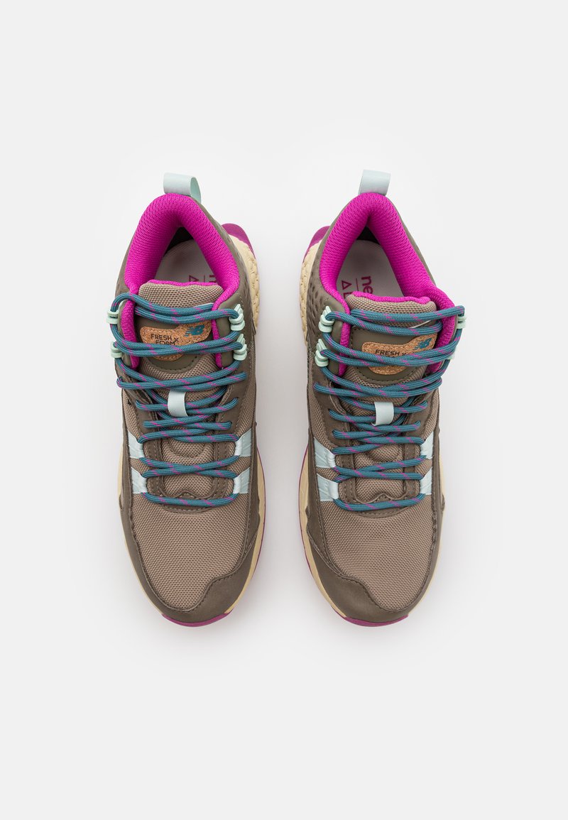 Zapatillas deportivas marrones para exteriores con parte superior de malla, cordones rosas y azules, y acentos en azul claro. Suela resistente con patrones texturizados para mayor agarre.