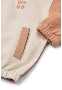 Cream and rust sweatshirt features a rounded neckline, elastic cuffs, a side pocket, and the text "WOOD" in rust embroidery. Soft texture.