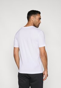 Fehér pamut póló klasszikus kerek nyakkal és rövid ujjakkal, lazább szabással és sima textúrával. Látható minták vagy díszítések nélkül.