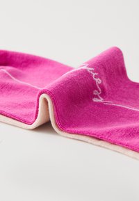 Rosa tekstil med en glat struktur, der har en hvid broderet detalje. Stoffet har en let glans og en kontrastfuld hvid kant.