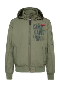 Olive green jacket with a hood, zip closure, and multiple pockets. Features text and logo graphics in navy and red accents. Textured fabric.