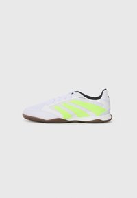 White indoor soccer shoe with neon yellow stripes, black inner lining, and brown sole, viewed from the left side.