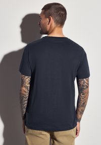 Námořnicky modré bavlněné tričko s kulatým výstřihem a krátkými rukávy, s hladkou texturou a rovný střihem. Minimalistický design.