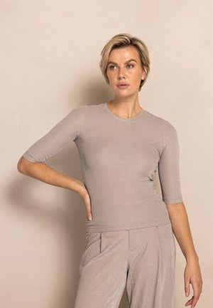 Hellbeiges, figurbetontes Oberteil aus Strickstoff mit dezentem Glanz. Verfügt über kurze Ärmel und einen rund ausgeschnittenen Halsausschnitt, kombiniert mit passenden Hosen.