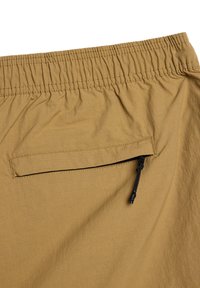 Pantaloni corti beige con vita elastica, dotati di una tasca sul retro con zip nera e un tessuto leggero e testurizzato.