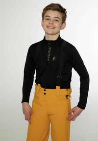 Černý top s dlouhým rukávem na zip a logem, doplněný žlutými lyžařskými kalhotami s nastavitelnými popruhy, knoflíky a boční kapsou.