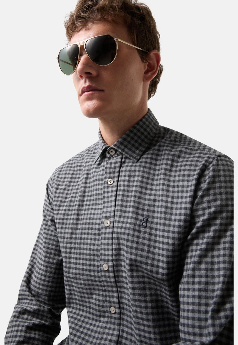 Herrenhemd in Grau und Schwarz mit Gingham-Muster und Button-down-Kragen, ausgestattet mit einem kleinen gestickten Logo und einer Knopfleiste. Dazu passende Sonnenbrille mit goldenem Rahmen.