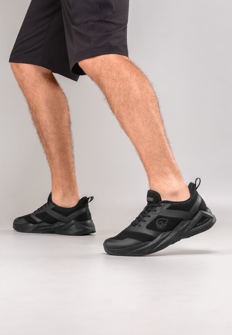 Schwarze Sportschuhe mit Obermaterial aus Mesh und synthetischem Material, ausgestattet mit einer strukturierten Gummisohle, gepolsterter Sohle und einem Logo an der Seite.