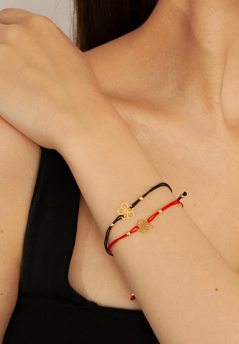 Czarno-czerwone bransoletki sznurkowe z złotymi zawieszkami w kształcie kwiatów i koralikami, prezentujące prosty, elegancki styl oraz kontrastową kolorystykę.