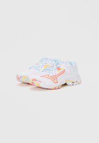 Baskets blanches avec des accents bleu clair, arborant un logo corail, des détails jaunes et une semelle à motif coloré.