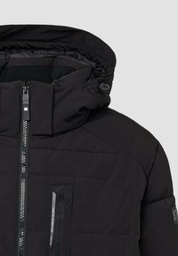 Zwarte gewatteerde jas met een hoge kraag, ritssluiting en een klein voorvakje met een gestructureerde accent. Glad stoffen afwerking.