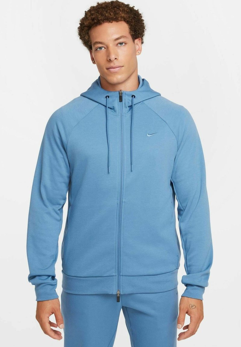 Blauer Reißverschluss-Hoodie aus weichem Stoff, mit einer Kapuze mit Kordelzug, Raglanärmeln und einem kleinen Logo auf der Brust.