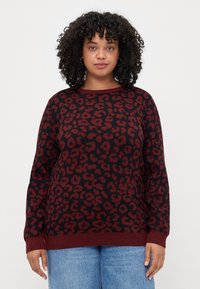 Sweater com padrão de leopardo em marrom e preto, com mangas longas e decote redondo. Bainha e punhos canelados. Textura de malha suave.