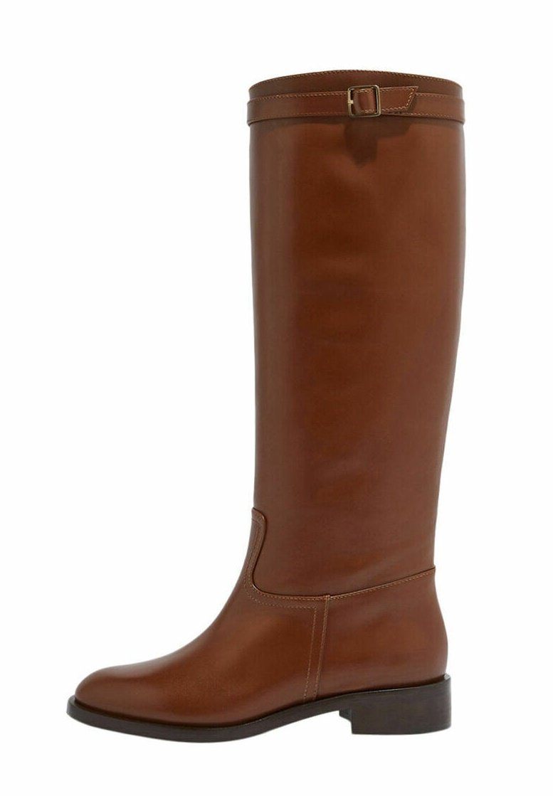 Bota de cuero marrón hasta la rodilla con punta redonda, ligero tacón y correa decorativa con hebilla en la parte superior. Textura suave y diseño elegante.