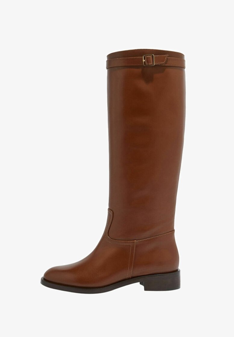 Bota de cuero marrón hasta la rodilla con punta redonda, ligero tacón y correa decorativa con hebilla en la parte superior. Textura suave y diseño elegante.