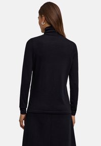 Schwarzer Rollkragenpullover aus weichem Material, mit langen Ärmeln und taillierter Silhouette, nahtlosem Design und gerippten Akzenten.