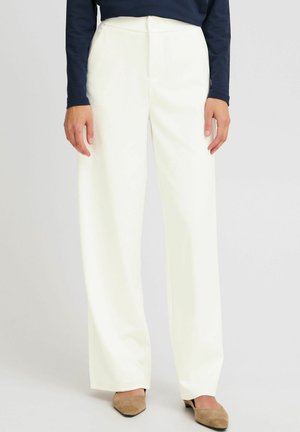 Pantalones de pierna ancha blancos con una textura suave, con cierre de botón y bolsillos. Combinados con una blusa de manga larga azul marino y zapatos beige.