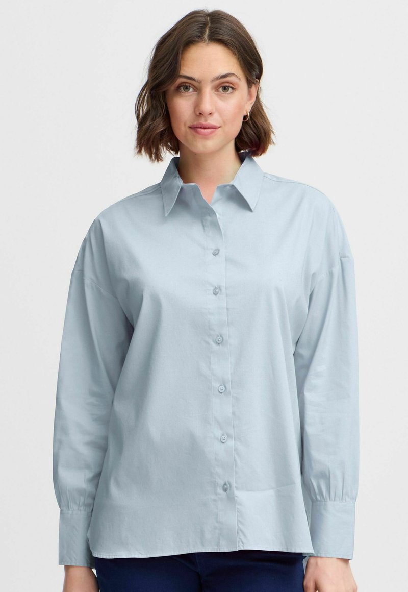 Light blue button-up shirt with a collar, long sleeves, and a relaxed fit. Fabric appears smooth with a minimal sheen.