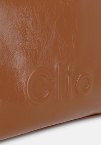 Sac en faux cuir marron avec logo "Clio" embossé, texture lisse avec une finition légèrement froissée, forme rectangulaire.