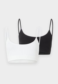 Δύο ραμμένα crop tops με λεπτές τιράντες, ένα λευκό και ένα μαύρο, εμφανίζονται πάνω σε απλό ανοιχτό φόντο.