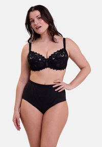 Soutien-gorge en dentelle noire avec des bords en feston et une surface texturée, associé à une culotte haute noire présentant un motif de couture géométrique.