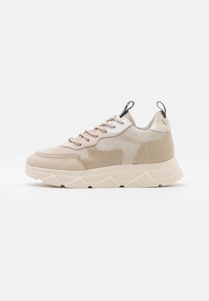 Sneaker beige con tomaia liscia e testurizzata, con dettagli in stampa coccodrillo, chiusura con lacci frontale e una suola spessa e angolosa.