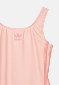 Top de desporto rosa com decote em U, feito de tecido suave, apresentando o logo da Adidas ao centro e um discreto detalhe franzido na gola.