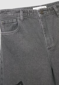 Jeans in denim grigio con due tasche, chiusura a bottone e passanti per cintura. Presentano una sottile texture e un dettaglio grafico nero.