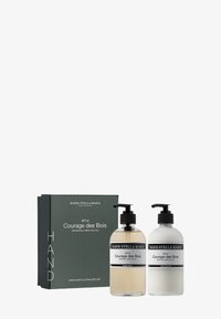 Ensemble de savon pour les mains et de lotion dans des bouteilles en verre transparent avec des pompes noires. La boîte est de couleur vert foncé avec du texte blanc présentant les détails du produit et le nom de la marque.