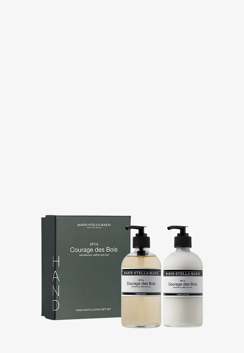 Ensemble de savon pour les mains et de lotion dans des bouteilles en verre transparent avec des pompes noires. La boîte est de couleur vert foncé avec du texte blanc présentant les détails du produit et le nom de la marque.