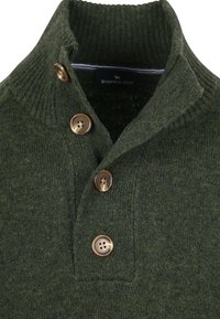 Dunkelgrüner gerippter Strickpullover mit hohem Kragen und vier braunen Knöpfen auf der Frontleiste.