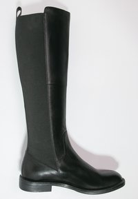 Bota alta de cuero negro con panel lateral elástico, punta redondeada, tacón bajo y lengüeta en la parte trasera sobre fondo blanco.