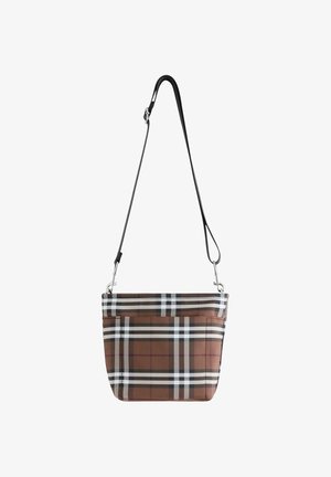 Brun, sort og hvid ternet crossbody taske med justerbar sort rem og foran lomme, hængende mod en hvid baggrund.