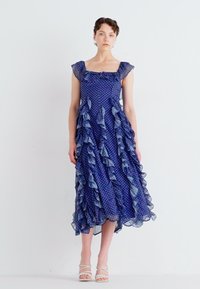 Vestido azul con lunares, con acentos fruncidos en los hombros y el dobladillo, hecho de una tela ligera, presenta una silueta fluida y un diseño hasta la rodilla.