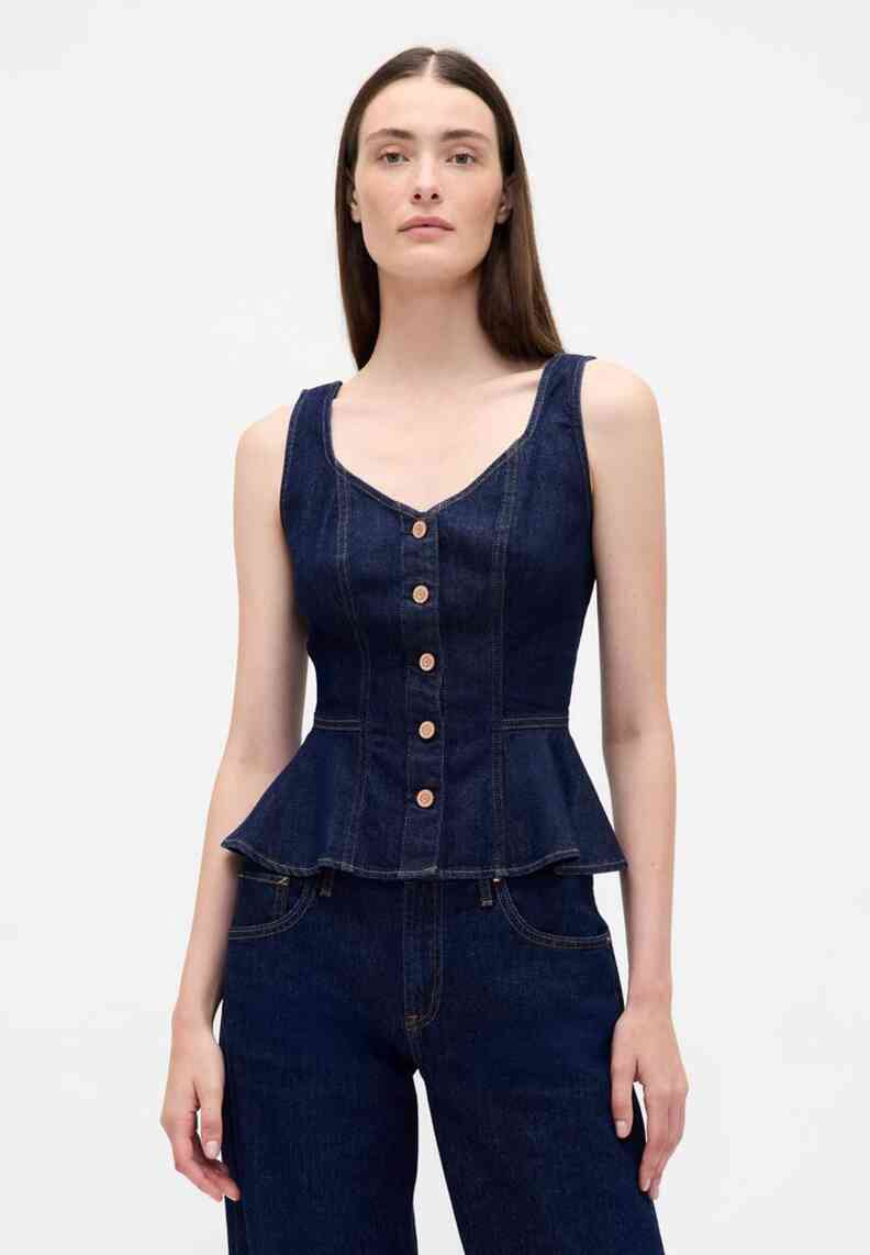 Tume sinise teksariidest peplum-top, kaarjakaelusega, nööpidega ees ja rõhutatud vöökohaga. Omab laiu rihmasid ja lehvikukujulist serva.