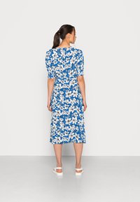 Vestido azul com flores, com mangas curtas e bufantes. Apresenta uma cintura ajustada e uma saia midi fluida. Padrão floral branco em todo o vestido.