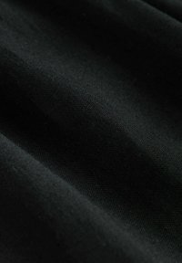 Fekete szövet textúrált felülettel, amely finom ráncokat és puha, sima megjelenést mutat. Az anyag szilárdnak és sűrűnek tűnik.
