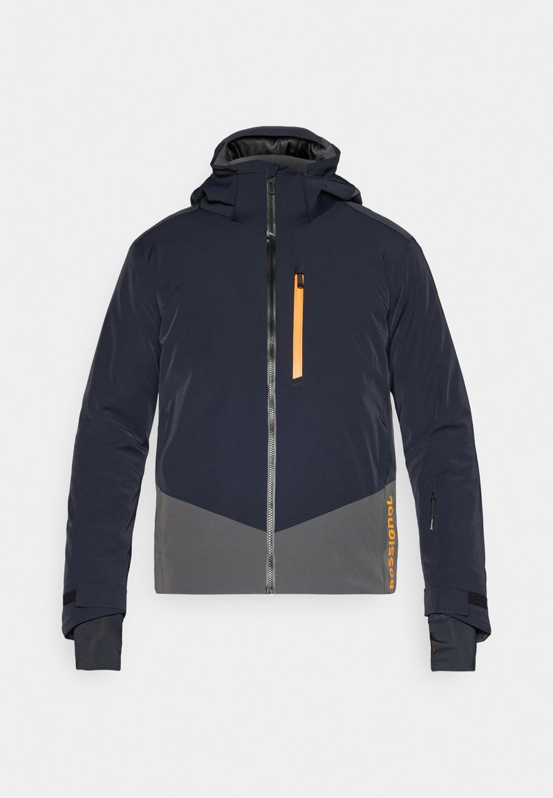 Giacca isolante da uomo in blu navy con dettagli grigi. Presenta un colletto alto, tasche con zip e un dettaglio della zip di colore arancione. Polsini elastici.