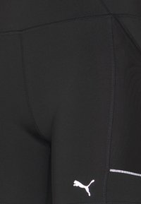 Czarne spodenki sportowe z elastycznego materiału, z białym logo Puma i kontrastowym przeszyciem. Zawierają detal z kieszenią na zamek.