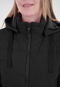 Schwarze Puffjacke mit hohem Kragen, verfügt über einen Frontreißverschluss und eine verstellbare Kordel, hergestellt aus strukturiertem, isoliertem Material.
