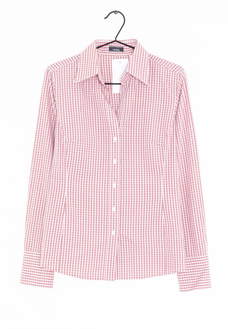 Chemise à manches longues à carreaux rouges et blancs avec un col large suspendue sur un cintre noir sur fond blanc.